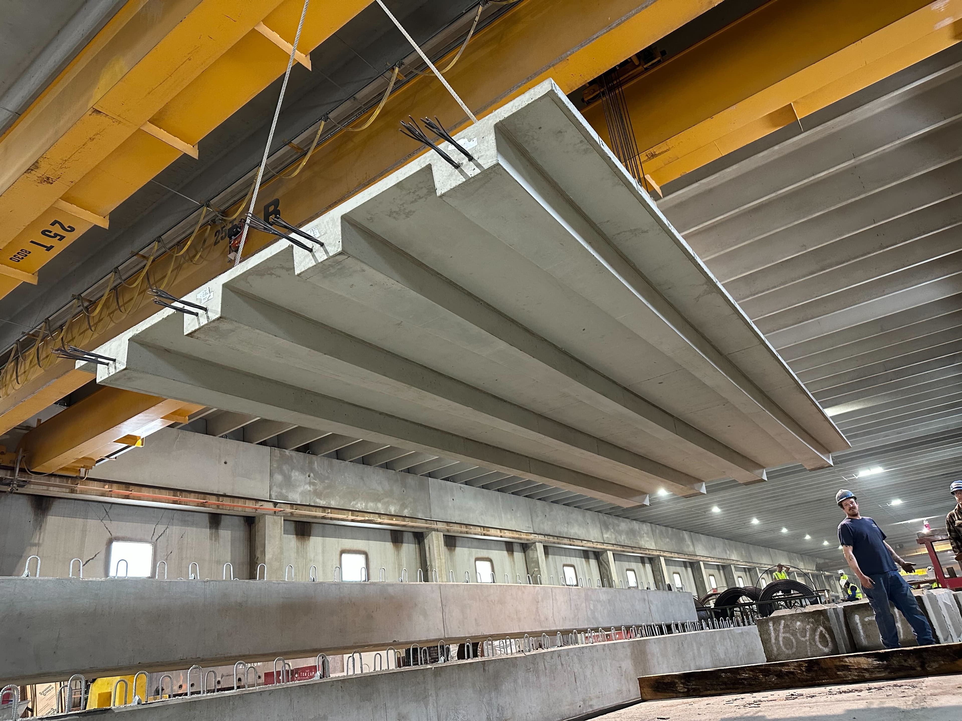 Shape-optimized multi-stemmed precast floor slab lifted by overhead crane at the J.P. Carrara & Sons plant